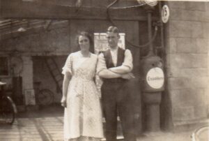 The addition of a large lean-to extension on the left hand side of Sonny Coombs' shop. Nelly Coombs and her son Bill standing outside the extension with hand operated pumps.